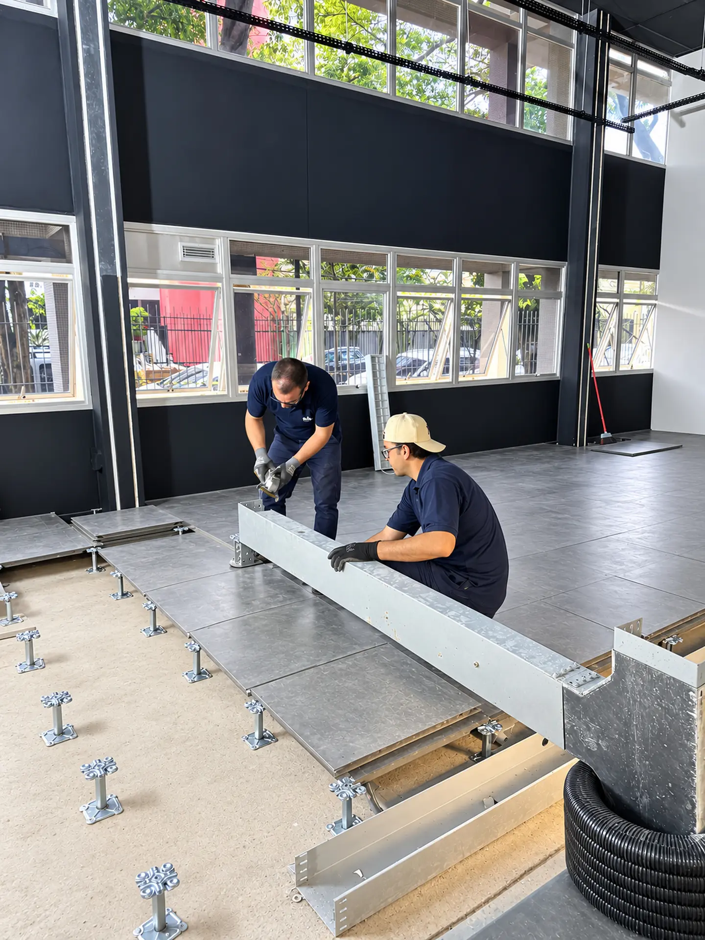 Equipe montando eletrocalhas sob o piso elevado