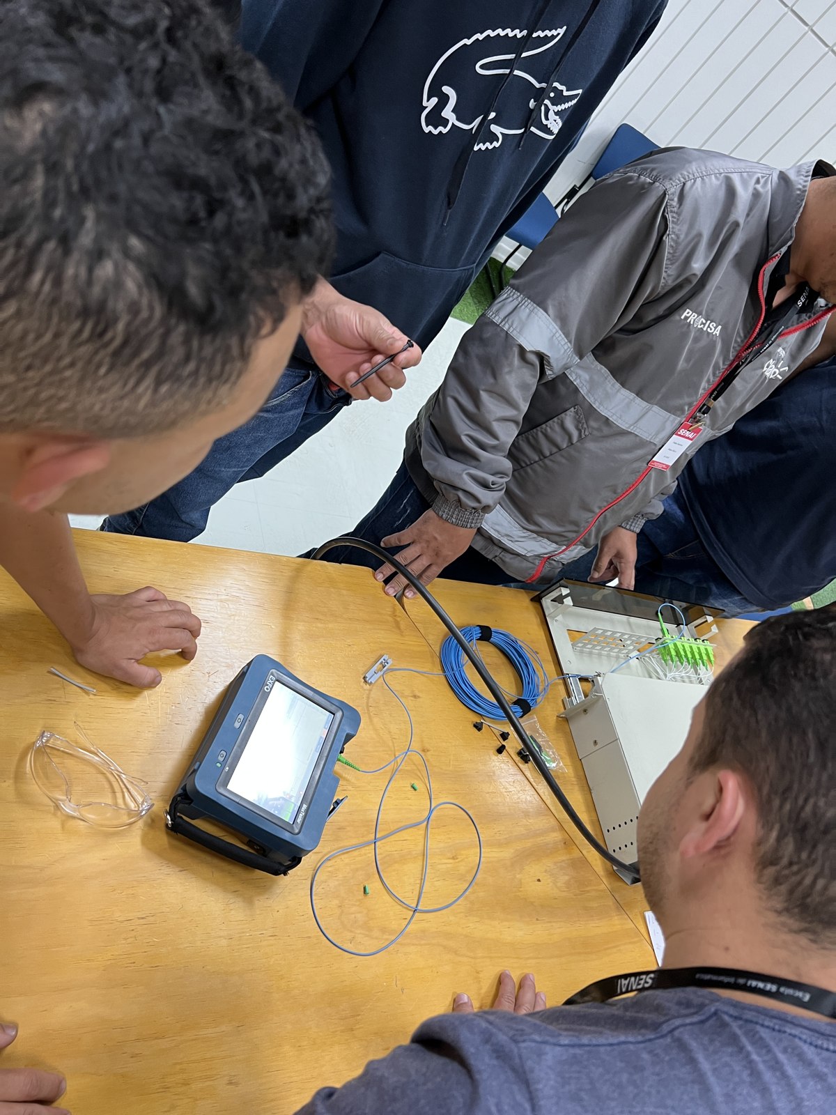Grupo acompanhando uma medição com OTDR em uma bancada de fibra óptica